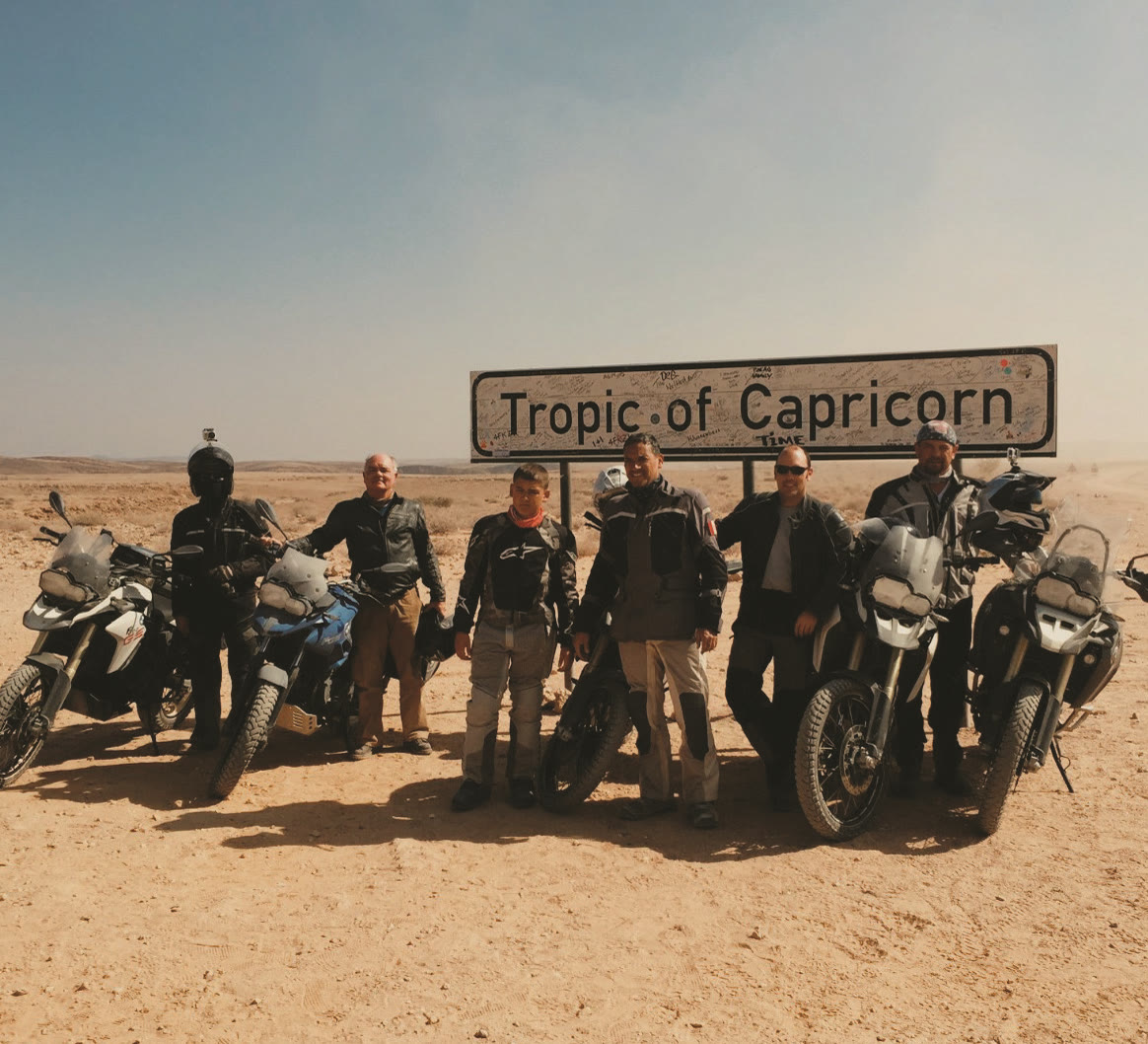 T3M riders and motorcycles at the Tropic of Capricorn sign in Namibia