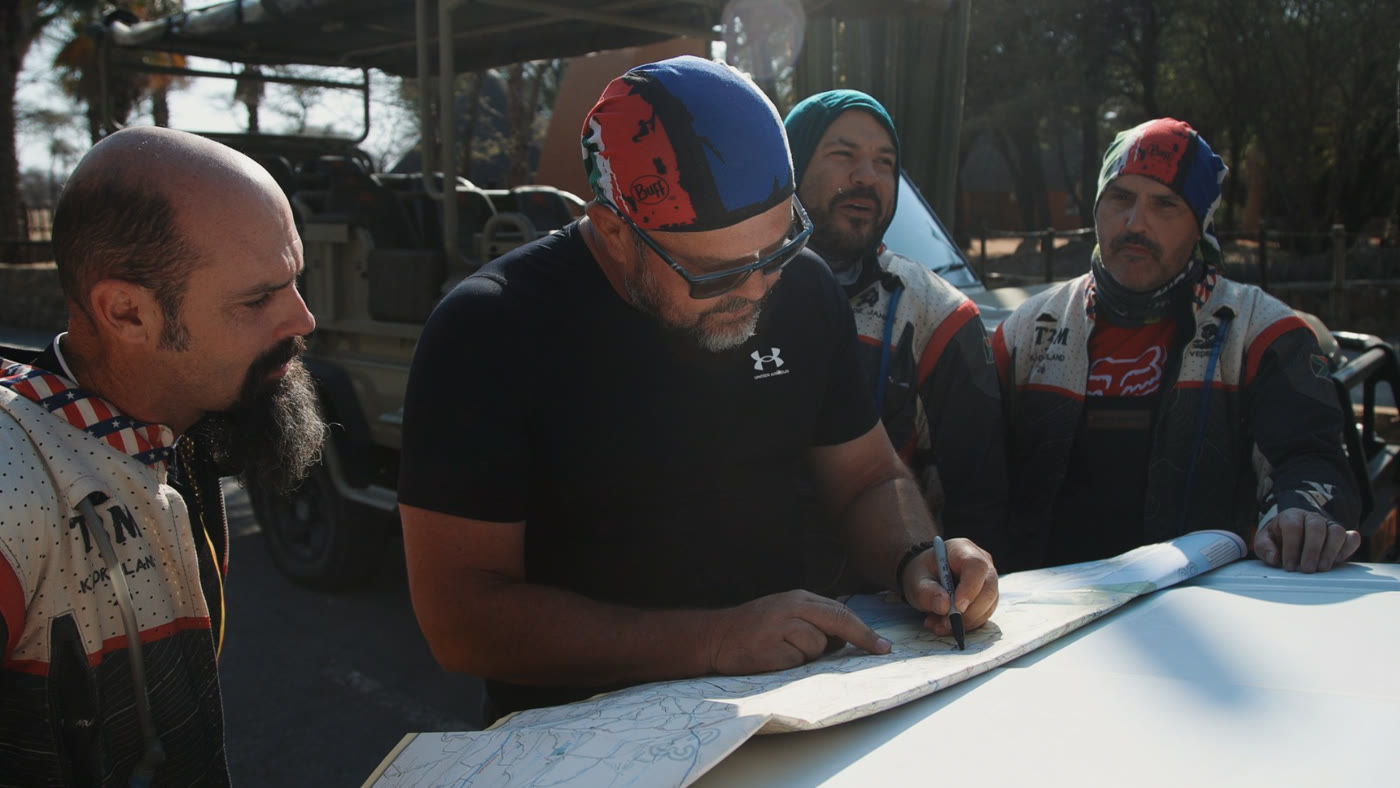 Aldo and riders planning the route over a paper map